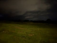 a grassy field with dark clouds in the background