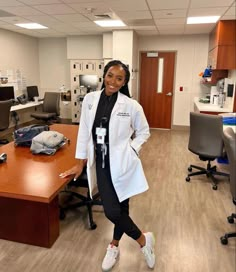 a woman in a white lab coat standing next to a desk