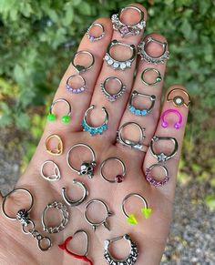 a person's hand holding several pairs of rings in different colors and sizes, all on top of each other