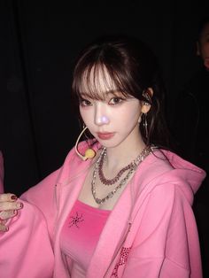 a young woman wearing a pink jacket and necklace