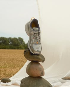 a pair of shoes sitting on top of rocks in front of a white cloth covered field