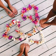 two people standing on a wooden floor with flowers arranged in the shape of a heart