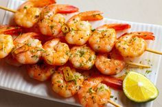 shrimp skewers with lemon wedges and garnish on a white plate