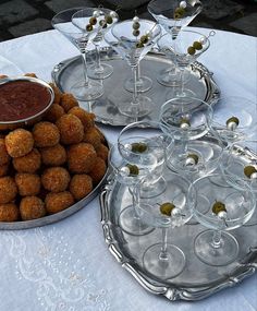 there are many glasses and trays with food on the table next to each other