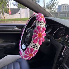 the steering wheel cover is decorated with pink and white crocheted flowers on it