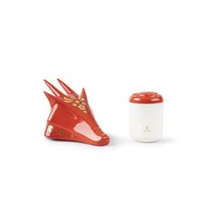 a red and white ceramic animal head next to a cup