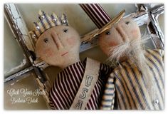 two cloth dolls with crowns and ribbons on their heads, one is wearing a crown