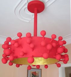 a red and gold chandelier hanging from the ceiling in a room with pictures on the wall