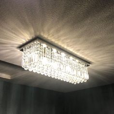 a crystal chandelier hanging from the ceiling in a room with black walls and curtains