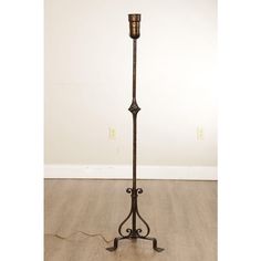 an antique floor lamp on a wooden floor with a white wall in the back ground