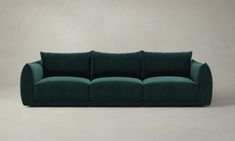 a green couch sitting on top of a white floor next to a gray wall in an empty room