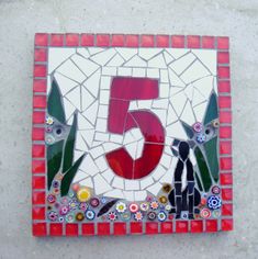 a red and white mosaic tile with the number five in it's center surrounded by flowers