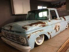 an old blue truck with rusted paint on it's hood parked in a garage