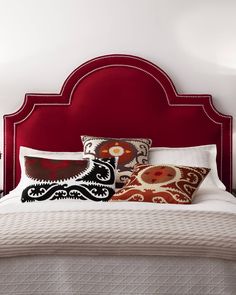 a bed with red headboard and pillows on it