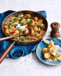 a pan filled with food on top of a blue cloth next to a wooden spoon