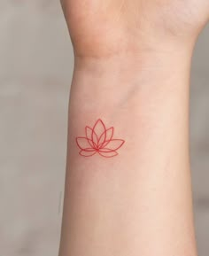 a red tattoo on the wrist of a woman with a lotus flower in her left arm