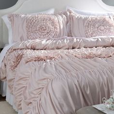 a bed with pink comforter and pillows on it