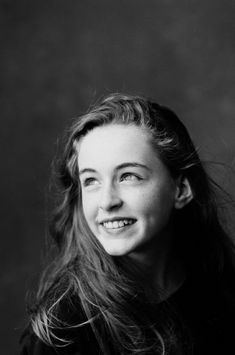 a black and white photo of a young woman with long hair smiling at the camera