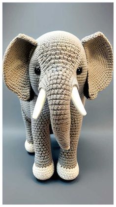 an elephant made out of knitted yarn with tusks and ears is shown in front of a gray background