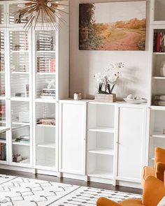 a living room filled with lots of furniture and bookshelves on top of white shelves