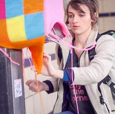 a woman sitting on top of a refrigerator next to a colorful object in the air