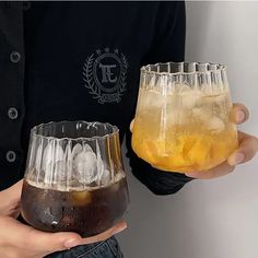 two people holding glasses with drinks in them