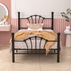 a bedroom with pink and white walls, a black metal bed frame and a mirror on the wall