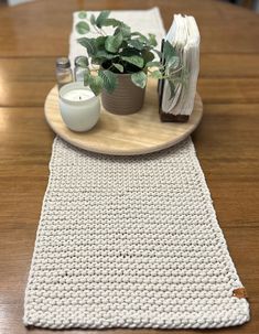 a wooden table topped with a white crocheted place mat and a potted plant