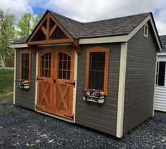 a small shed with two windows and flowers in the window boxes