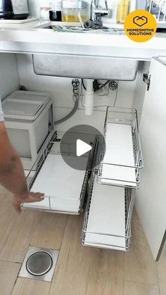 a man is standing in front of a sink and looking at the bottom drawer open