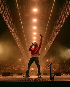 a man standing on top of a stage with his arms in the air