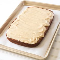 a piece of bread with frosting on it sitting on a tray next to a fork