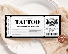 a white plate topped with a black and white ticket to a tattoo convention event on top of a table