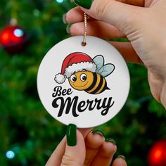 someone holding up a christmas ornament with a bee on it