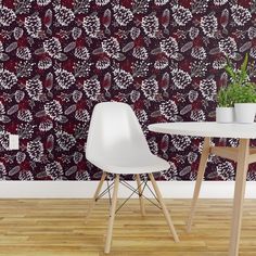 two white chairs and a table in front of a wall with a red pattern on it