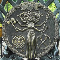 a metal plaque with an image of a woman holding two axes and the moon above her head