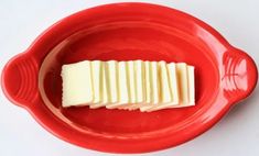 a red bowl filled with sliced cheese on top of a white table