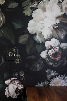 the wall paper has flowers on it and is black with white, gray and green leaves