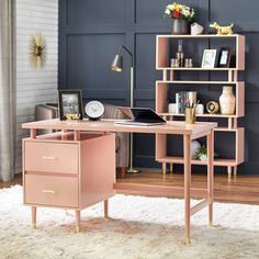 a pink desk with two drawers in front of a bookshelf and shelving unit