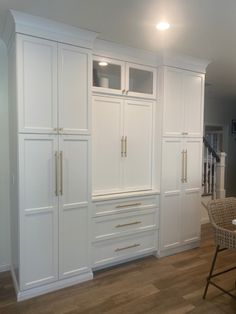 an empty kitchen with white cabinets and chairs in the center, along with a dining room table