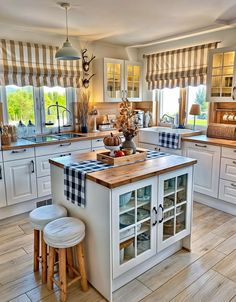 a kitchen with an island and stools next to the counter top in front of two windows