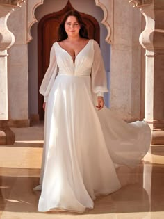 a woman in a white wedding dress standing on a tile floor with her arms behind her back