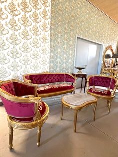 a living room filled with furniture next to a wallpaper covered in gold and red