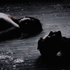 two people laying on the ground with their heads down