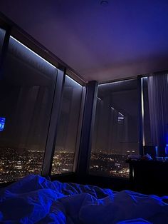 a bedroom with a view of the city lights at night from it's windows