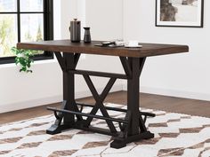 a wooden table sitting on top of a rug in front of a window with a plant