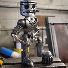 a metal figurine is standing on top of a piece of workbench