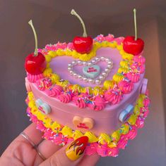 a heart shaped cake decorated with cherries and candy canes is being held by a hand