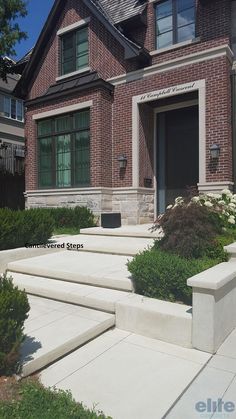 a house with steps leading up to the front door and landscaping in front of it