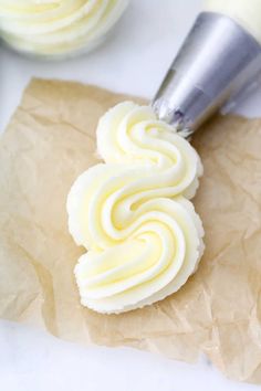 a cupcake being frosted with white icing on top of brown parchment paper